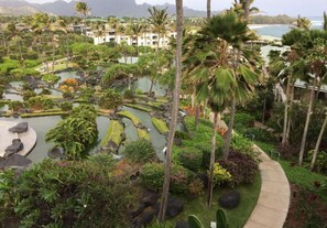 A resort with a landscaped garden, palm trees, and a view of the ocean.