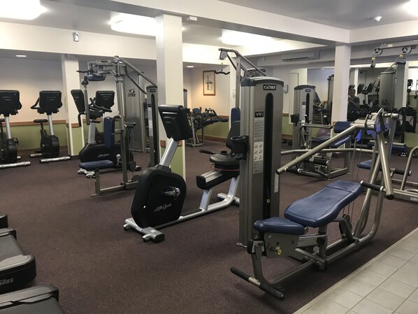 A gym with various exercise equipment, including treadmills, weight machines, and a bench press.