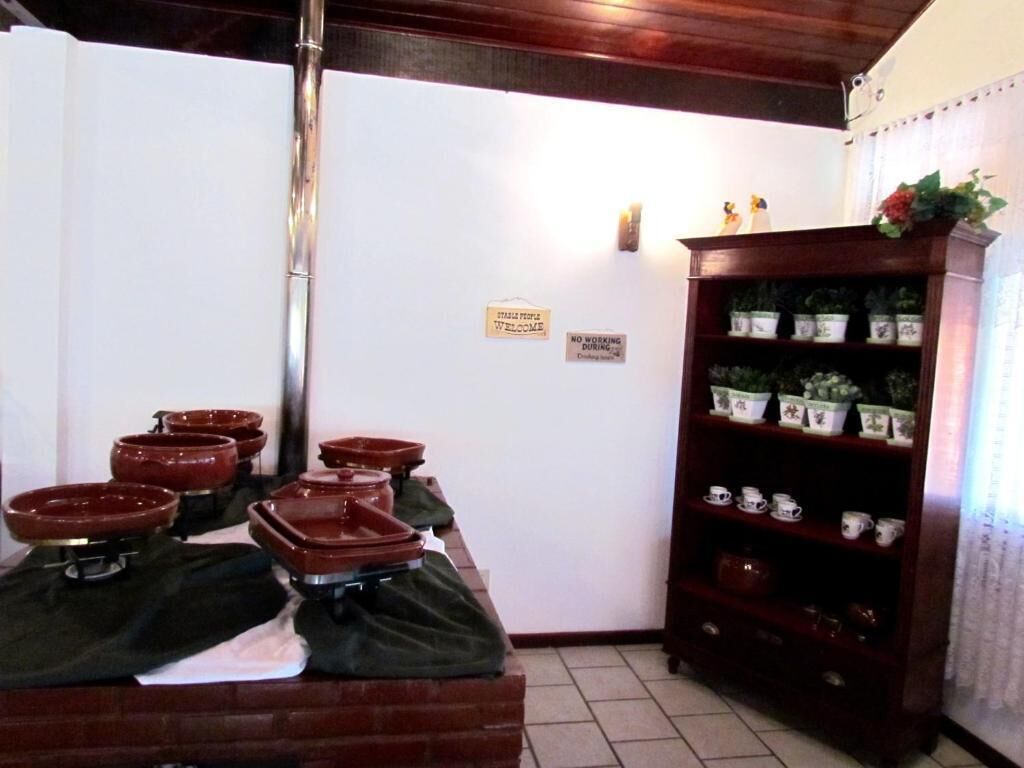 A room with a brick counter displaying several red bowls, a wooden cabinet with tea cups, and a 'No Working During' sign on the wall.