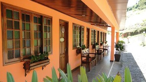 Un pasillo de hotel con puertas de madera, ventanas amplias y plantas en macetas.