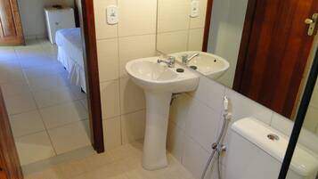 A bathroom with a pedestal sink, a mirror, a toilet, and a shower.