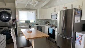 A modern kitchen with stainless steel appliances, a wooden dining table, and a built-in oven. - Beachfront Home with Outstanding Beach Views; Quick Walk to Ocean. (Matagorda)