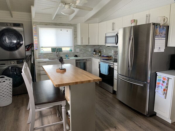 A modern kitchen with stainless steel appliances, a wooden dining table, and a built-in oven. - Beachfront Home with Outstanding Beach Views; Quick Walk to Ocean. (Matagorda)
