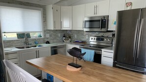 A modern kitchen with white cabinets, stainless steel appliances, and a wooden island. - Beachfront Home with Outstanding Beach Views; Quick Walk to Ocean. (Matagorda)