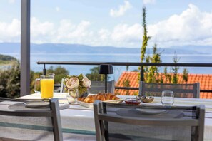 Uma mesa de café da manhã com croissants, um copo de suco de laranja e um vaso de flores.