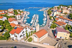 Uma marina com barcos atracados, cercada por edifícios residenciais com telhados vermelhos.