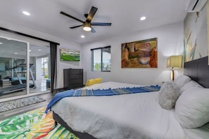 A bedroom with a bed, a ceiling fan, a TV, a painting, and a window. - Casa Del Sol: #259070 Pool, Spa, Game Room, Court (La Quinta)