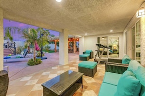 A covered outdoor area with seating, a treadmill, and a view of the pool area. - Casa Del Sol: #259070 Pool, Spa, Game Room, Court (La Quinta)