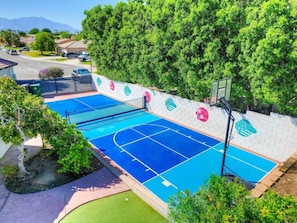 An outdoor basketball court with a net, surrounded by a brick wall with decorative elements. - Casa Del Sol: #259070 Pool, Spa, Game Room, Court (La Quinta)