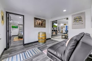 Un salon moderne avec un canapé en cuir, un tonneau en bois et un téléviseur fixé au mur.
