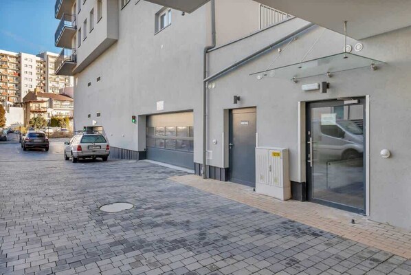 Un edificio moderno con zona de estacionamiento, puerta de garaje y entrada de vidrio.