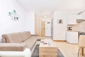 Un salon moderne comprenant un canapé, une table basse et un coin cuisine avec un réfrigérateur et une cuisinière.
