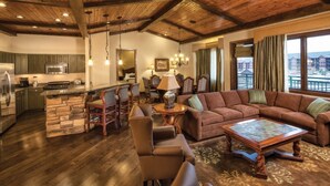 A spacious living area with a large couch, a dining table, and a kitchen area with a stone island.
