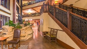 A spacious lobby with a grand staircase, seating areas, and a decorative rock feature.
