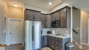 A modern kitchen with dark cabinets, stainless steel appliances, and a granite countertop. - Deck, Hot Tub, Views! Reunion Retreat in Ozarks (Linn Creek)
