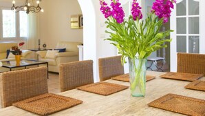A dining area with a wooden table, wicker chairs, and a vase with purple flowers. - Del Pozo by Interhome (Calpe/Calp)