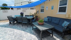 Una terrazza esterna con tavolo, sedie, divano e una pianta in vaso.