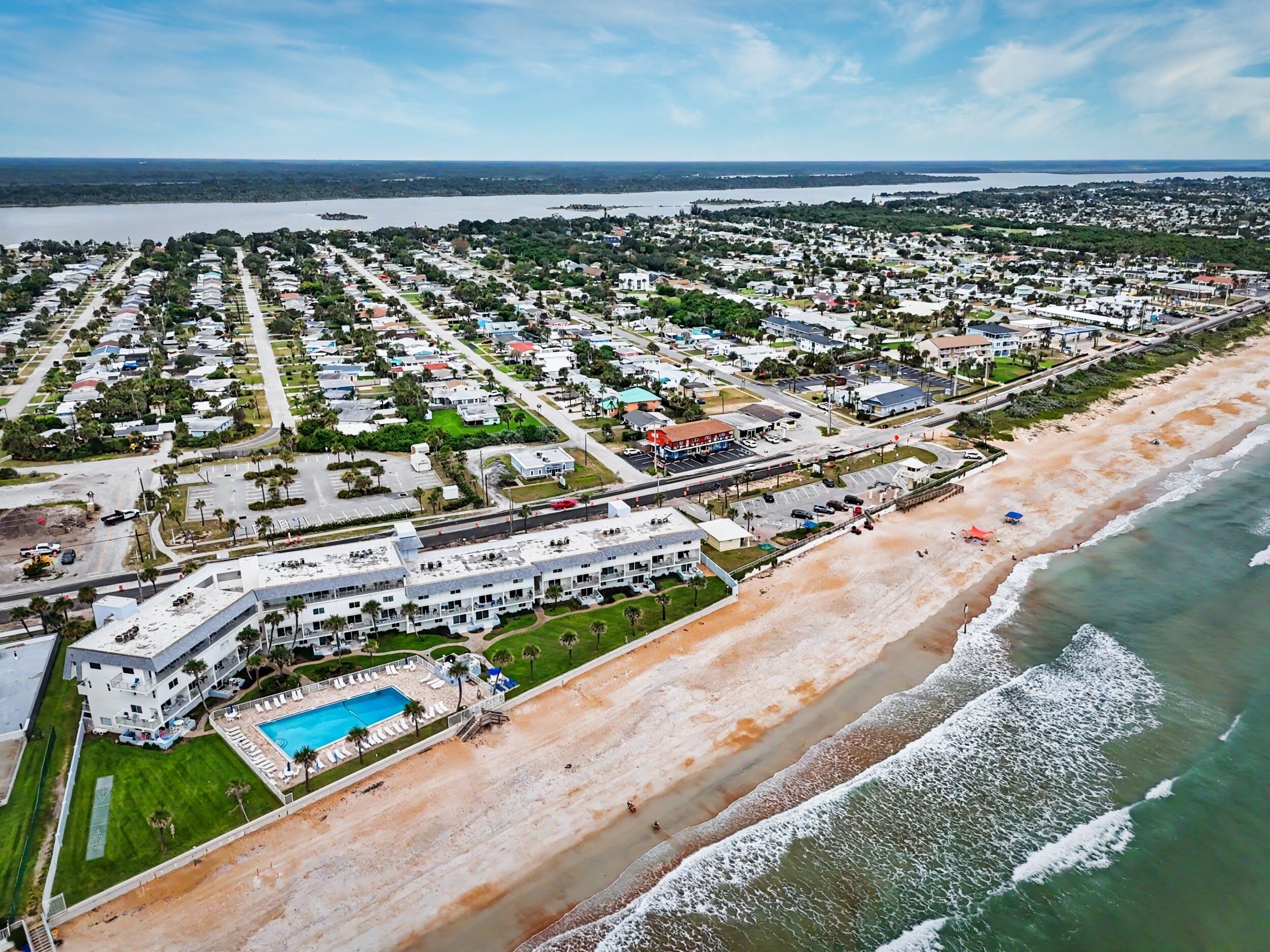 A coastal residential area with a beachfront hotel featuring a swimming pool and a beach view.
