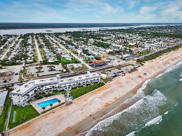 Zona residencial costera con un hotel frente al mar, piscina y vistas a la playa.