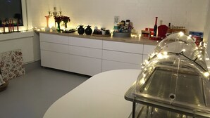Et moderne køkken med hvide skabe, en emhætte i rustfrit stål og forskellige køkkenartikler på bordet.