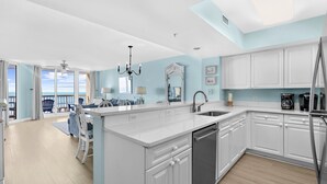 A modern kitchen with white cabinetry, a central island, and a view to the outside.