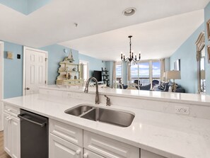 A kitchen with a large island, a double sink, and a dishwasher. - Coastal Calm | 316 COV |  Oceanfront Villa With Pool & Views (Folly Beach)