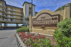 The Charleston Oceanfront Villas sign with a view of the building and a landscaped area with flowers. - Coastal Calm | 316 COV |  Oceanfront Villa With Pool & Views (Folly Beach)