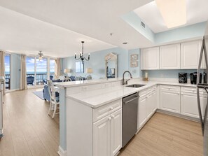 A modern kitchen with white cabinetry, a central island, and a view to the outside.