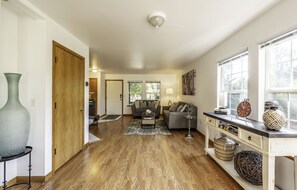 A spacious living area with a wooden floor, a sofa, a coffee table, and a console table with decorative items.