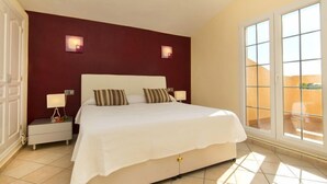 Camera da letto con un letto grande, due comodini, una finestra con vista e una parete rossa a contrasto.