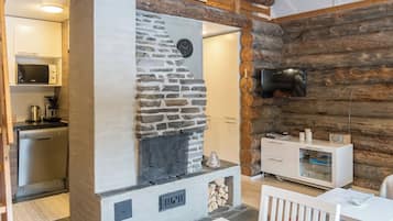 Une cuisine moderne avec une cheminée en pierre, des poutres en bois et un téléviseur fixé au mur, qui est également en bois.
