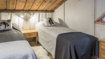 Un dormitorio acogedor con dos camas, cabecero de madera y una mesita de noche con lámpara.