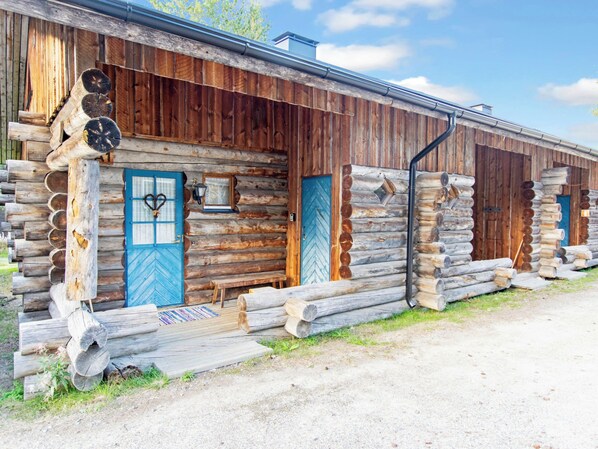 Une cabane en rondins avec une porte bleue, un petit porche et une fenêtre.