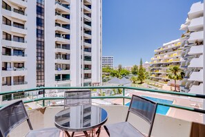 A balcony with a glass table and chairs, overlooking a pool and adjacent buildings. - Algamar Apartment - Vilamoura center (Vilamoura)