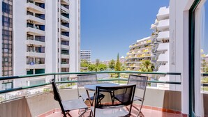 Un balcón con mesa y sillas, con vista a un paisaje urbano de edificios altos.