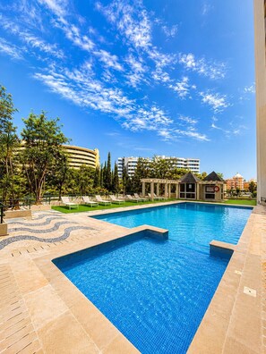 A swimming pool with a tiled deck, lounge chairs, and a pavilion. - Taalia I - Vilamoura (Vilamoura)