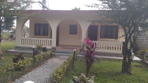 A building with a beige facade, arched windows, and a small porch. - Hotel Tress House (Sauraha)