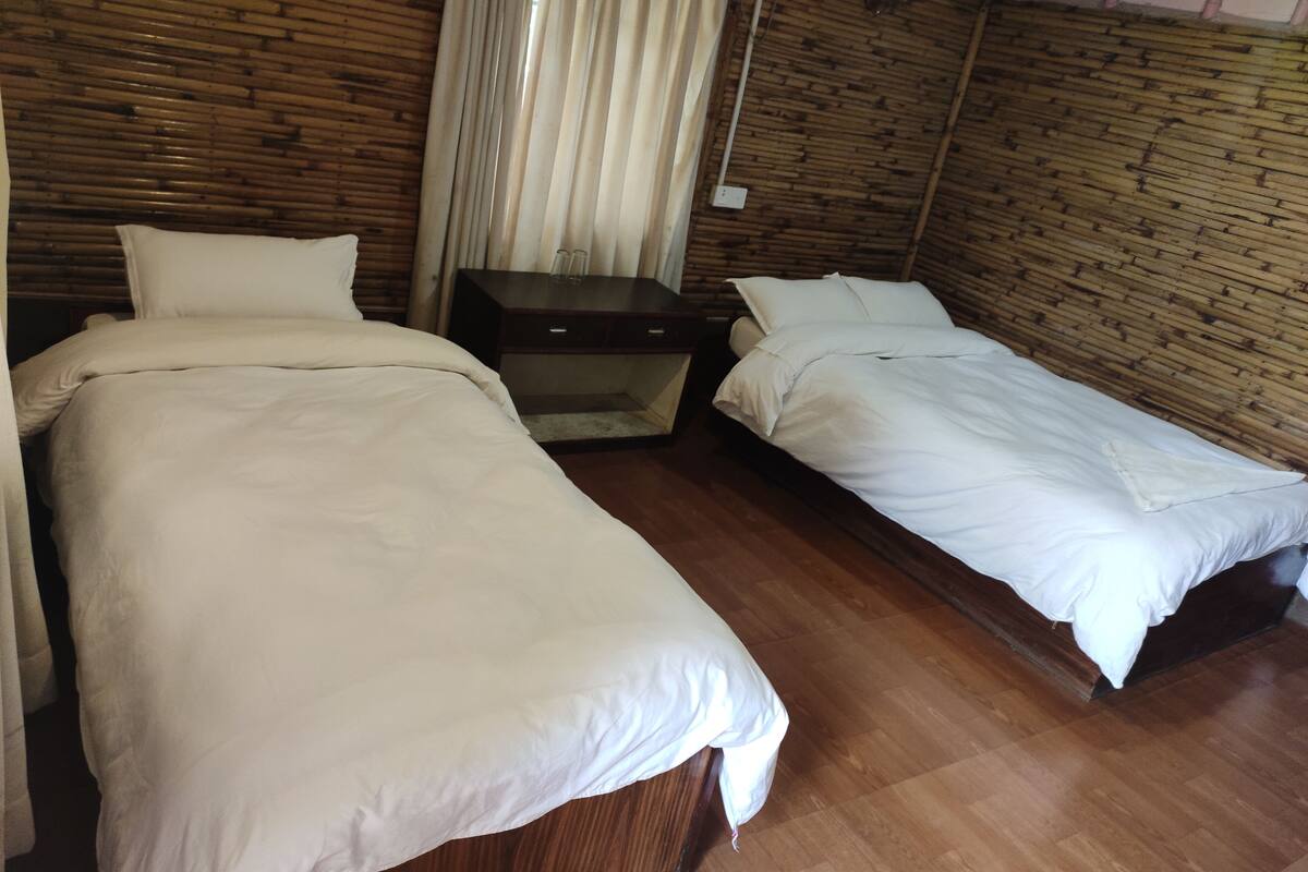A room with two beds, wooden flooring, and a wooden wall.