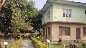 A pathway leading to a two-story building with a brick facade and multiple windows. - Hotel Tress House (Sauraha)