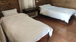 A room with two beds, wooden flooring, and a nightstand. - Hotel Tress House (Sauraha)