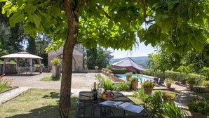 A patio area with a table and chairs, surrounded by potted plants and a swimming pool. - Vedi Torre by Interhome (San Gimignano)
