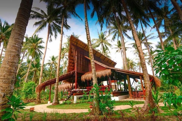 Un resort tropical con una estructura de techo de paja rodeado de palmeras.