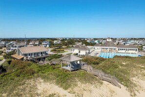 A coastal residential area with houses, a swimming pool, and a beach access deck. - Ocean Hideaway | Oceanfront | Community Pool (Nags Head)
