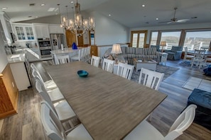 A modern kitchen with white cabinets, a large island, and a dining area with a wooden table and white chairs.