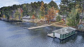 A lakeside property with docked boats, a floating house, and a dock extending into the water.