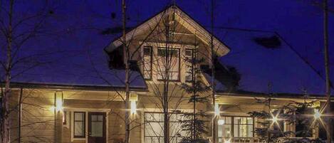 A two-story house with a sloped roof, a satellite dish, and a snow-covered front yard.