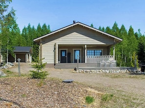 A two-story building with a front porch, a stone foundation, and a clear sky.