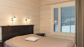 A bedroom with a bed, two wall-mounted lamps, a window with blinds, and a curtain.