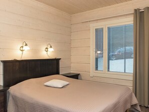 A bedroom with a bed, two wall-mounted lamps, a window with blinds, and a curtain.