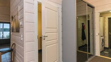 A hallway with a door leading to a bathroom, a chair, and a view of the outside.